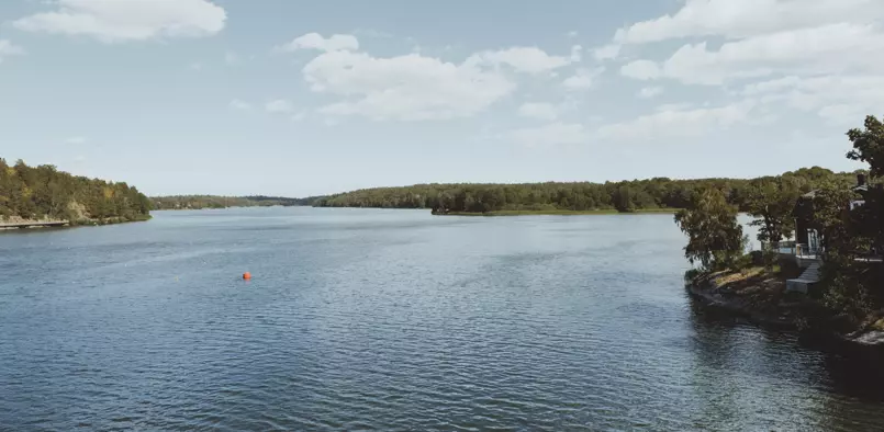Vy över sjön Magelungen, vattnet krusar sig lätt och skogen reser sig i bakgrunden.